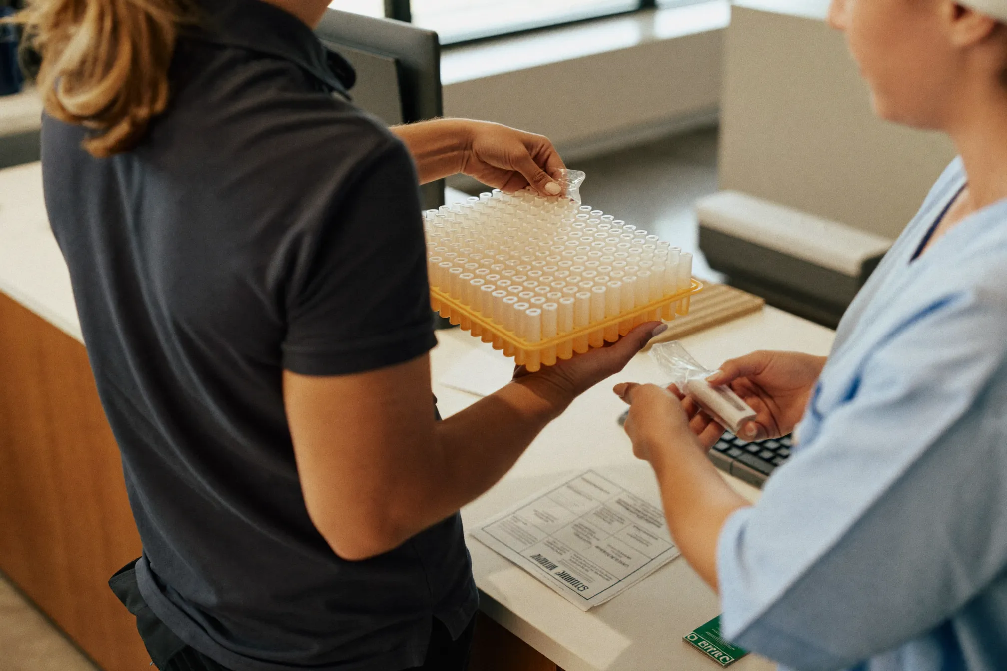 Medical courier delivering specimens to a lab technician at a clinic
